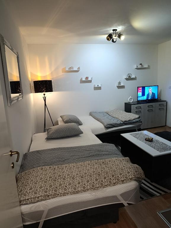 two beds in a room with a tv on the wall at Apartman Angela in Foča
