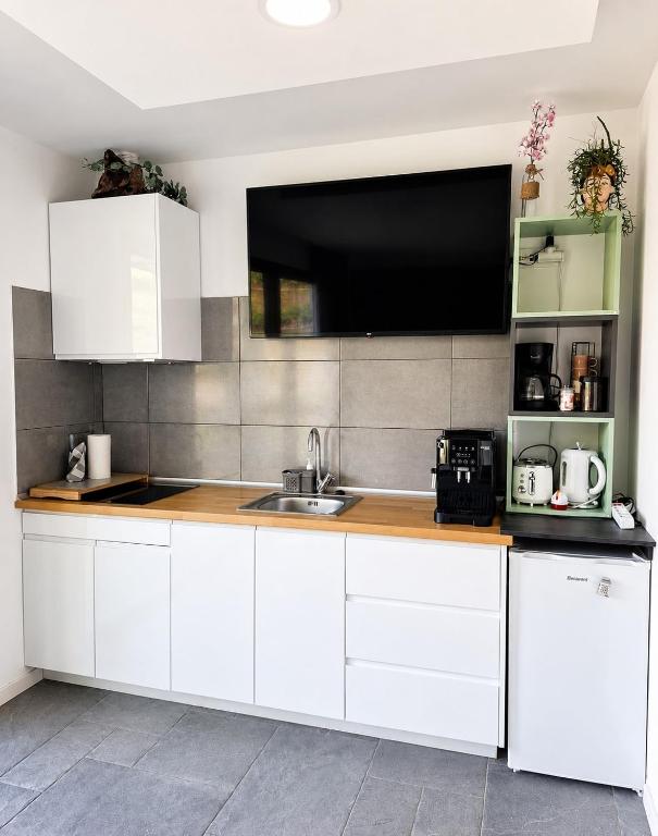 a kitchen with white cabinets and a flat screen tv at Villa Bavaria C in Ponta do Sol