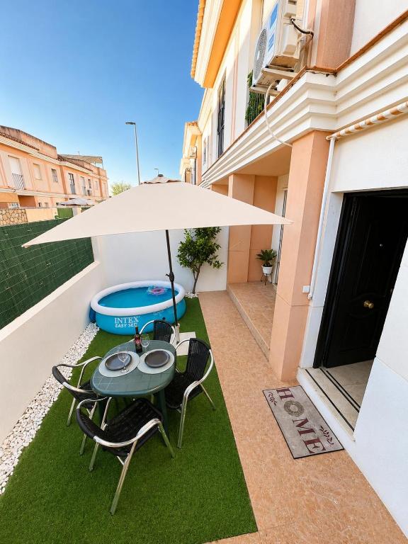 a table and chairs under an umbrella on a patio at Casa SOL y MAR junto a la PLAYA in Sanlúcar de Barrameda