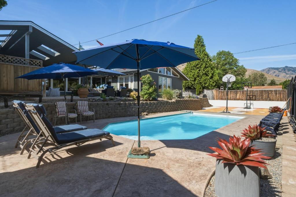 a swimming pool with a blue umbrella and a chair and a pool at Summer Fun Wenatchee home in Wenatchee