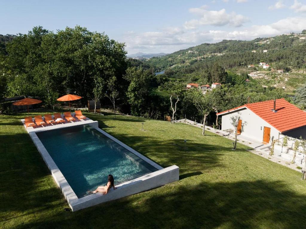 a woman sitting in a swimming pool in a yard at Passinhos House in Amarante