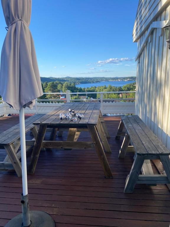 a wooden picnic table with an umbrella on a deck at Flott sørlandshus leies ut in Arendal