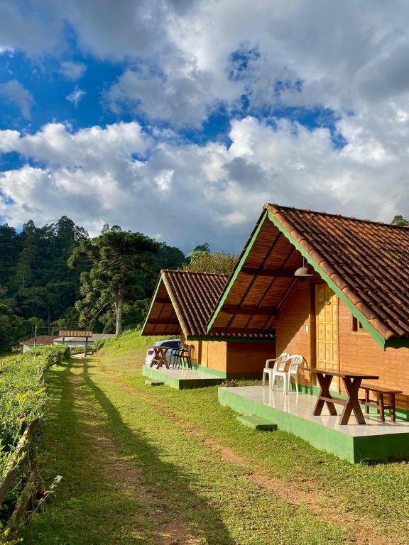 a building with a table and chairs in front of it at Chales Fazenda Cantinho do Selado in Monte Verde