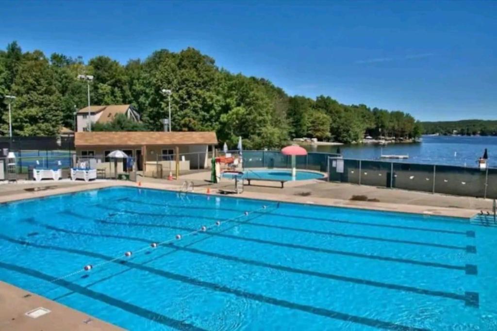 a large swimming pool next to a lake at Lake Luxe in Lake Ariel