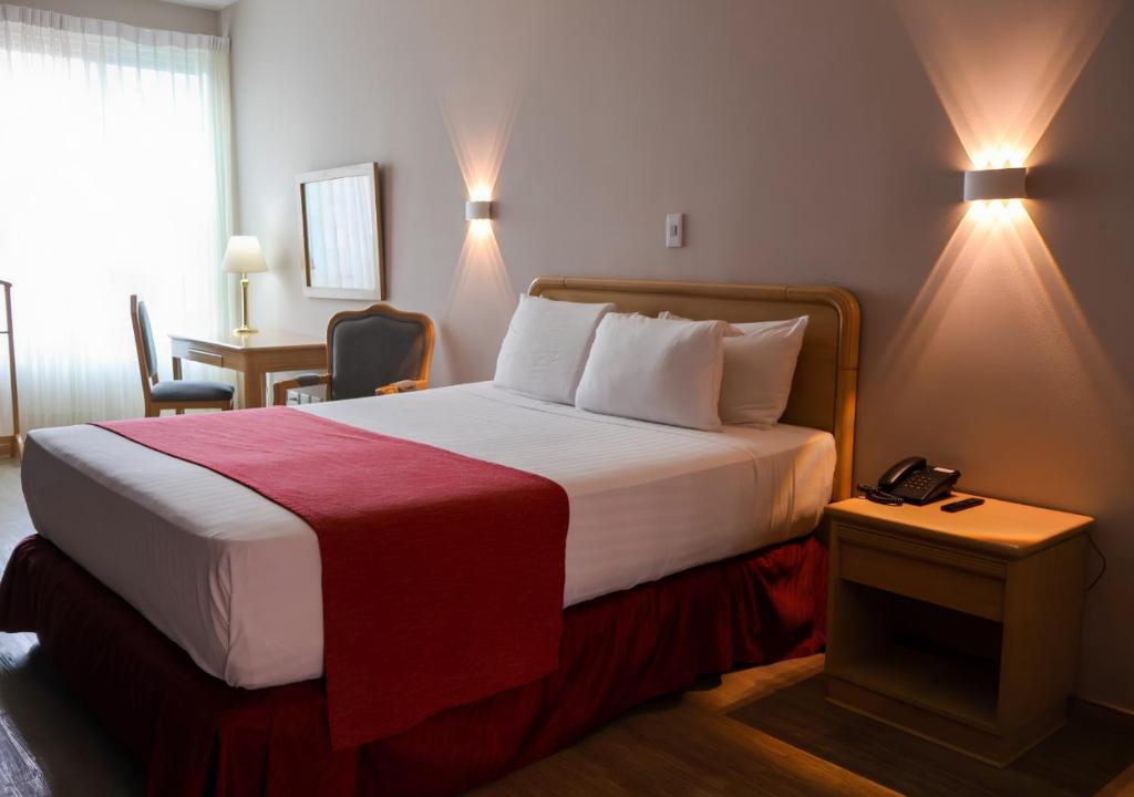 a hotel room with a bed with a phone on it at Hotel Internacional La Triada in Bucaramanga