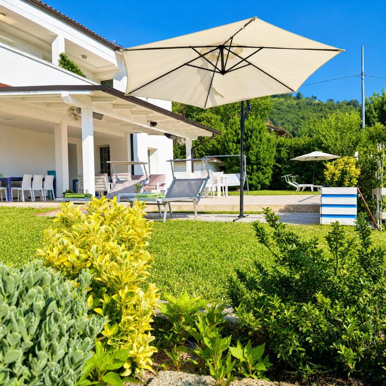 a house with a patio with an umbrella at TerrazzaPonente in Monte San Pietro