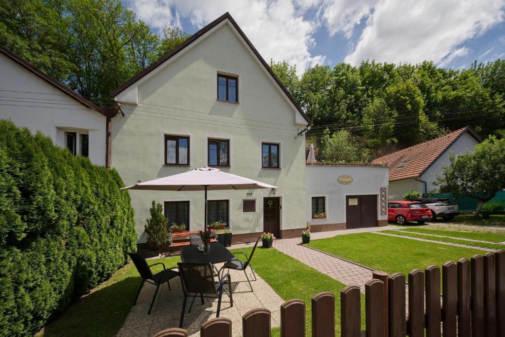 a house with a table and an umbrella in the yard at Penzion Sv. Duch in Český Krumlov