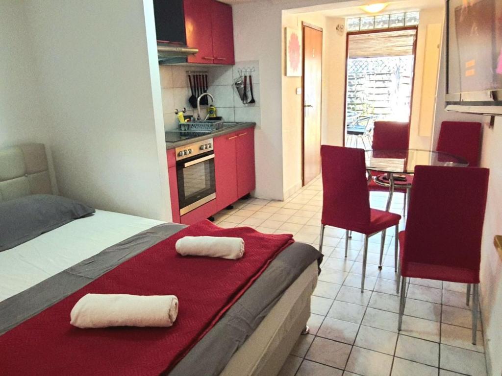 a room with a bed and a kitchen with red cabinets at UNIQUE Apartments Malinska in Malinska