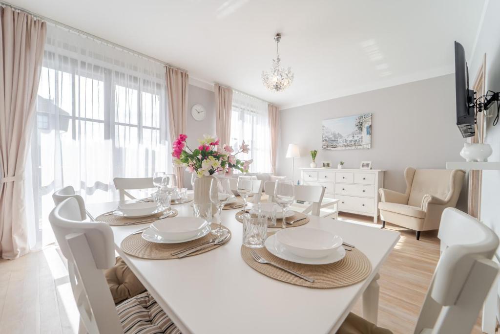 a white dining room with a white table and chairs at Apartament Prowansalski in Nałęczów