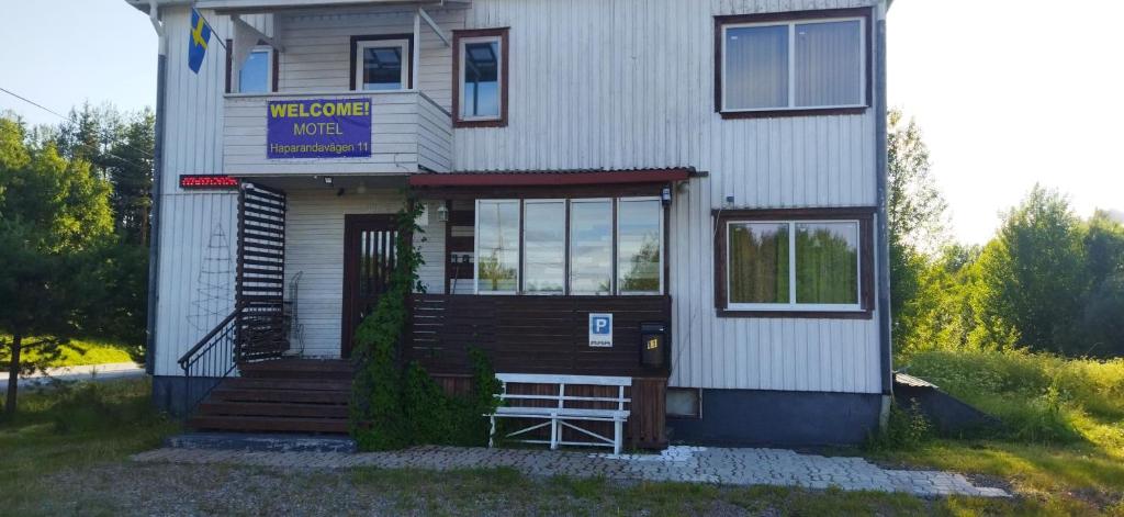 a white house with a sign that reads welcome home at Sangis Motel Haparandavägen 11 in Sangis
