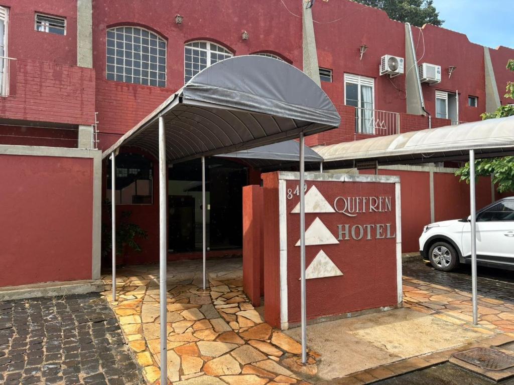a hotel sign in front of a red building at Quefren Residence Hotel in Uberaba