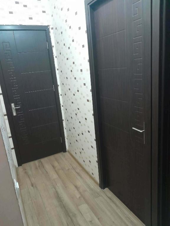 a hallway with two black doors and a wooden floor at ლაზები in Akhaltsikhe