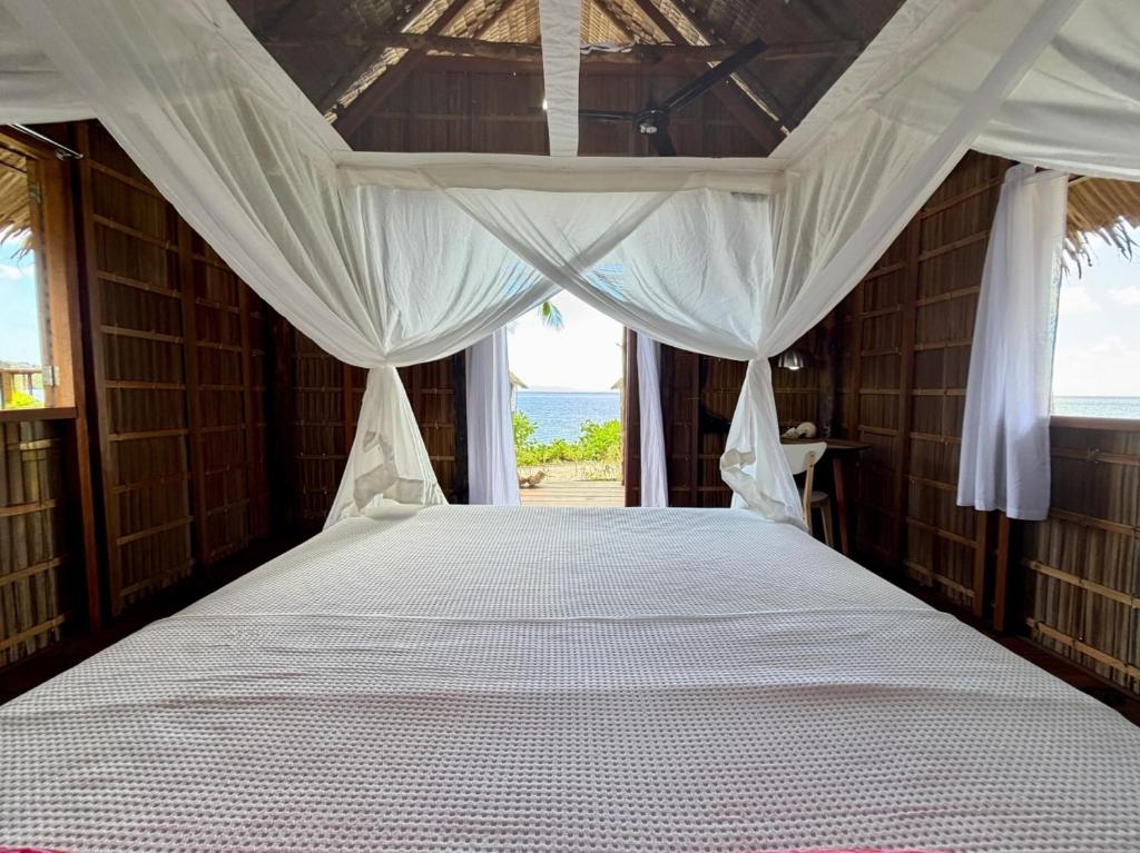 a bedroom with a canopy bed with a view of the ocean at ipyum Premium Beach Guest House in Sageurin