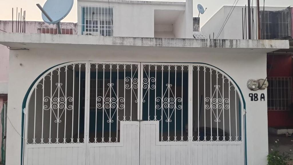 a white building with a gate in front of it at Casa naranjito in Cosoleacaque