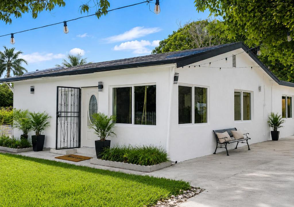 a white house with a bench in a yard at 05 Modern Co-Living Home with Newly Renovated Private Rooms Available in Miami