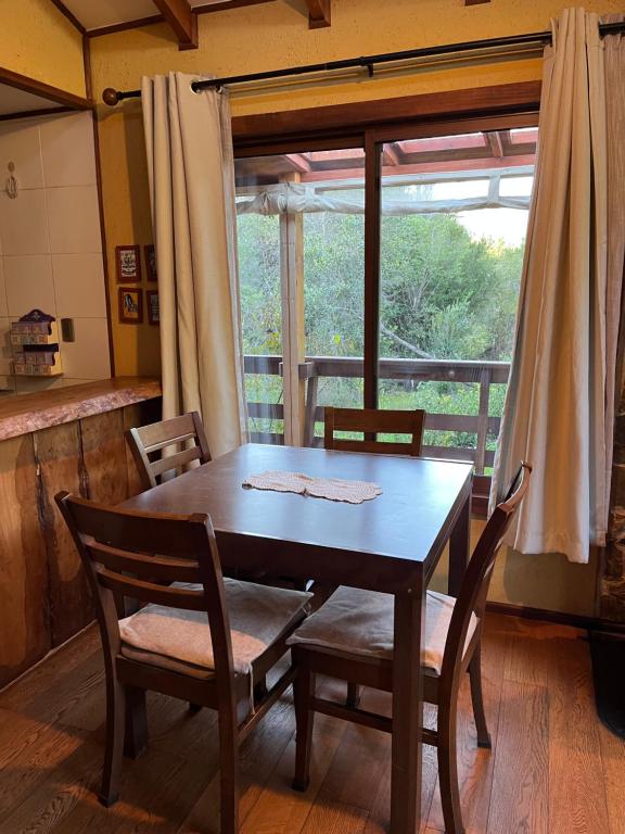 a wooden table and chairs in a room with a window at Refugio Lawentu Linares Colbun in Los Rabones