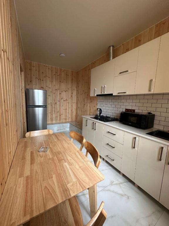 a kitchen with a wooden table and white cabinets at Guest House Ucha in Stantsiya Chakva