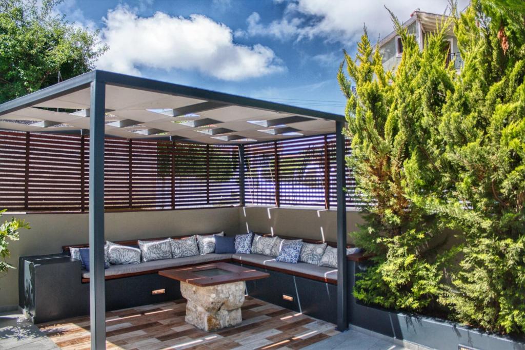 a pergola with a bench and a table on a patio at Casa Katrine in Lakíthra