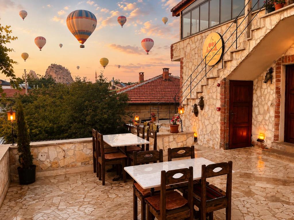 a patio with tables and hot air balloons in the sky at Cherrykonak cappadocia in Uçhisar