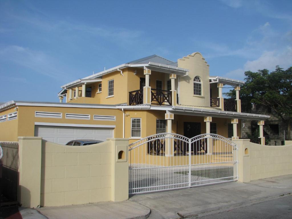 una casa amarilla con una puerta y una valla en Apartments in Maya's Bajan Villas en Christ Church