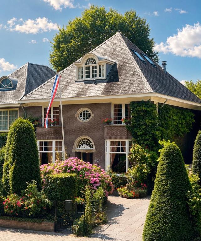 a house with bushes and flowers in front of it at Deventer Heritage en Boutique B&B, museumhuis "De Worp", het huis met de theekoepel, logeren in authentiek historisch erfgoed in Deventer
