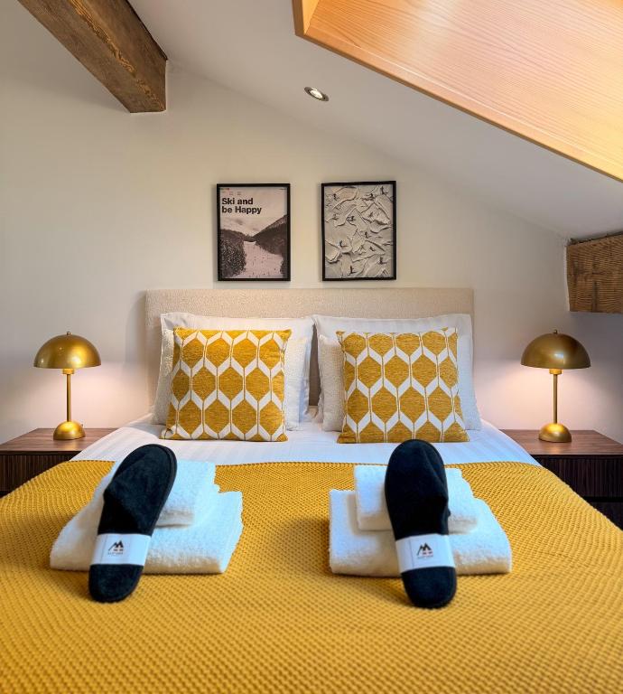 a bedroom with a bed with two pairs of slippers on it at ALP'INN Les Gets in Les Gets