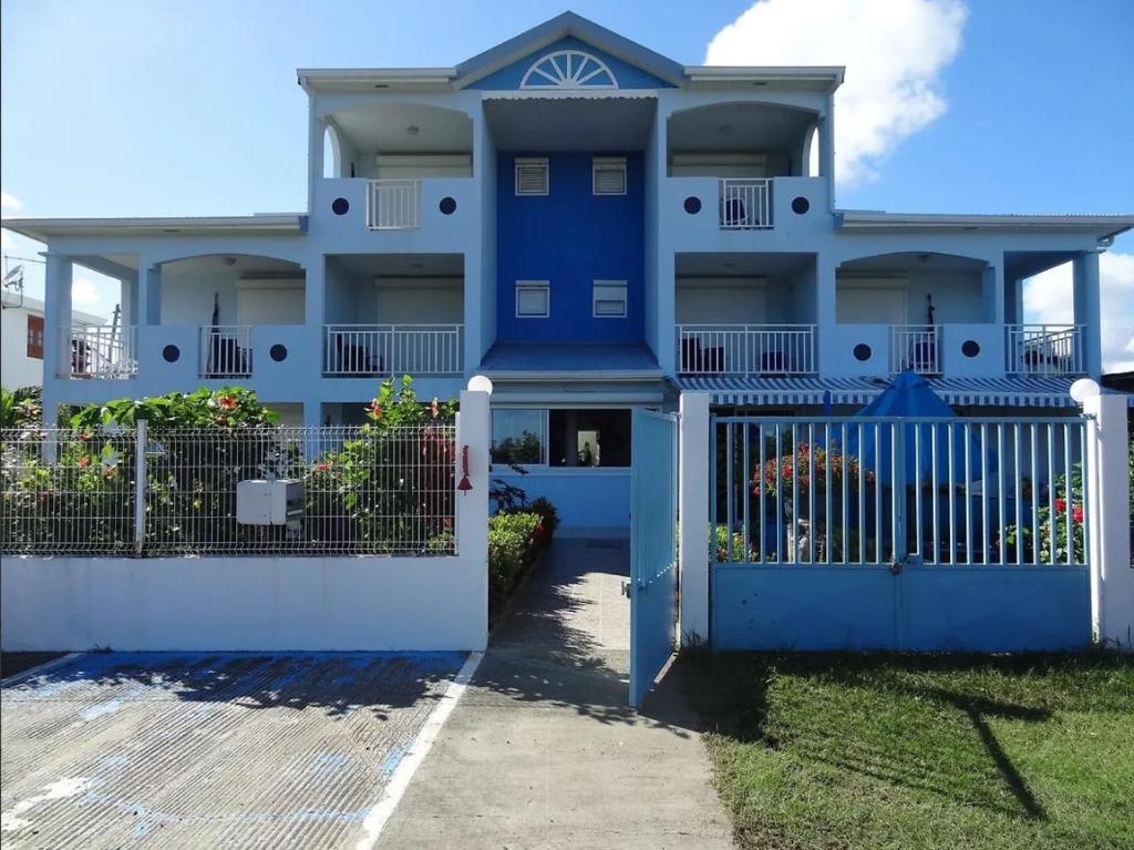 a blue house with a white fence at Le Paradis des Anges - Retraite spirituelle & Douceurs des Caraïbes in Le Vauclin