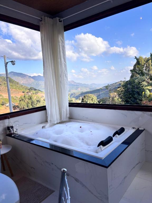 a bath tub in a room with a large window at Sítio Volta Fria in Pedra Menina