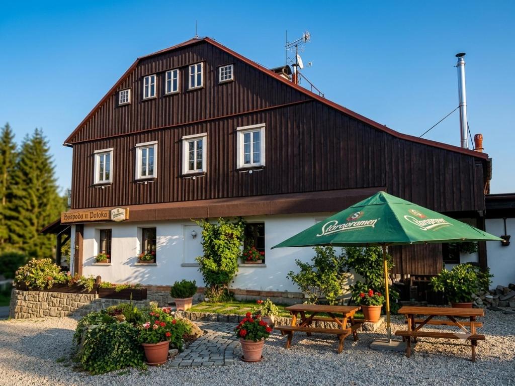 a building with a table and an umbrella at Když nevíte kam, přijeďte k nám penzion D'Artagnan in Kořenov