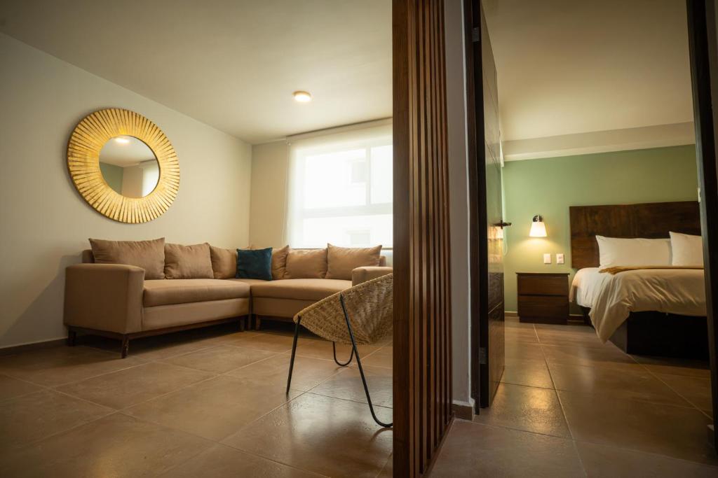 a living room with a couch and a bed and a mirror at Hotel Omenia in Tequisquiapan
