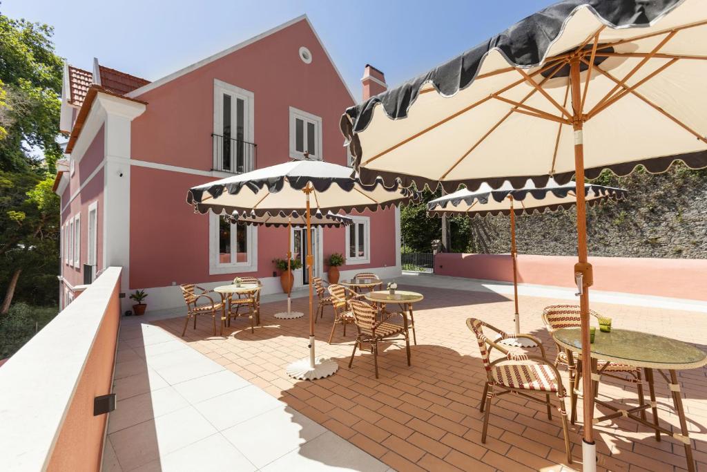 a patio with tables and chairs and umbrellas at Chalet Santo António in Sintra