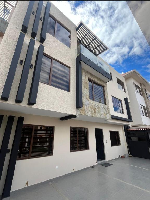 a white house with black doors and windows at Casa Central in Cuenca