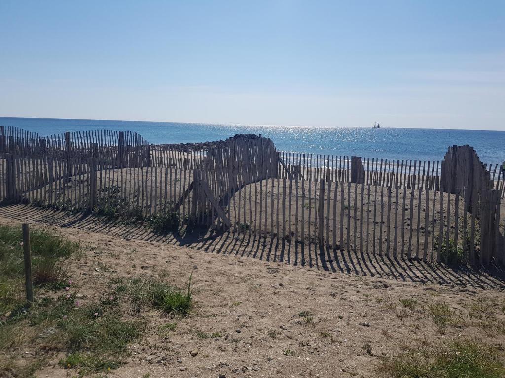 a fence on the beach with the ocean in the background at La Rose des Sables, T2 à la mer, terrasse et garage in Frontignan