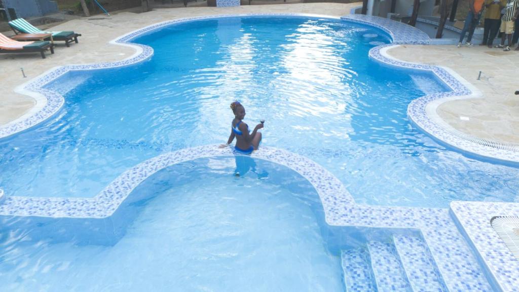 a woman is standing in a swimming pool at Musituni Luxury Villas in Diani Beach