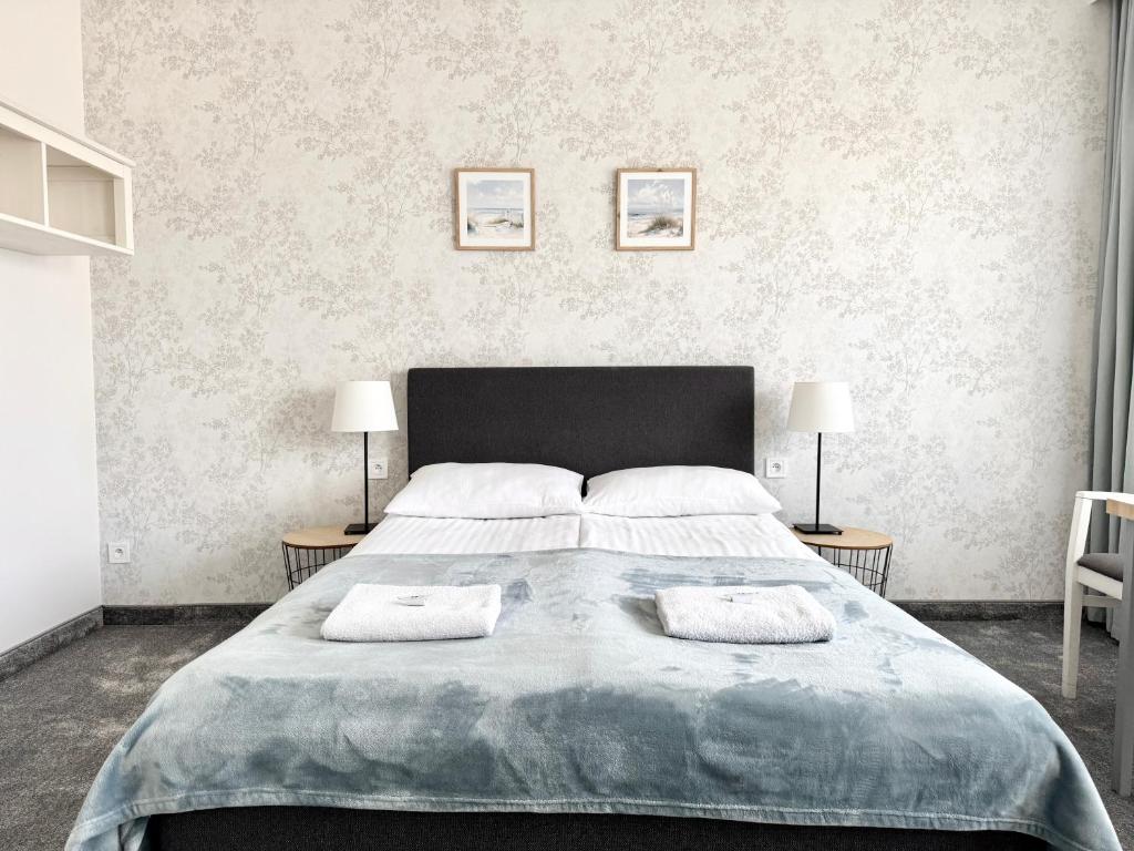 a bedroom with a large bed with two tables at Biały Domek - STREFA CISZY, CHILDREN FREE in Dźwirzyno
