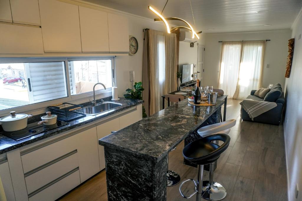 a kitchen with a granite counter top and a living room at Departamento de Lujo a 8 min del centro in San Nicolás de los Arroyos