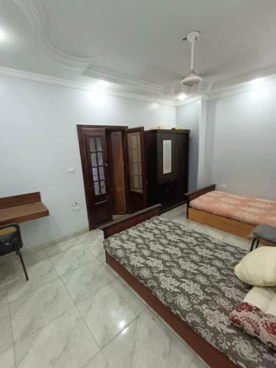 a bedroom with two beds and a desk in it at نورس هوم in Al Ghuşnah