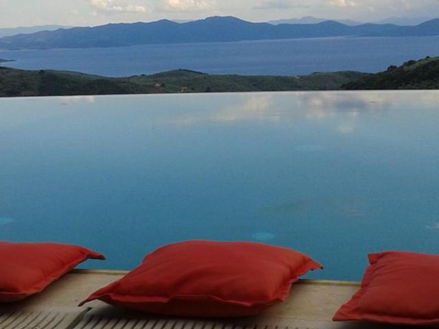 two red pillows sitting on a deck near the water at Hotel Dryalos in Mileai
