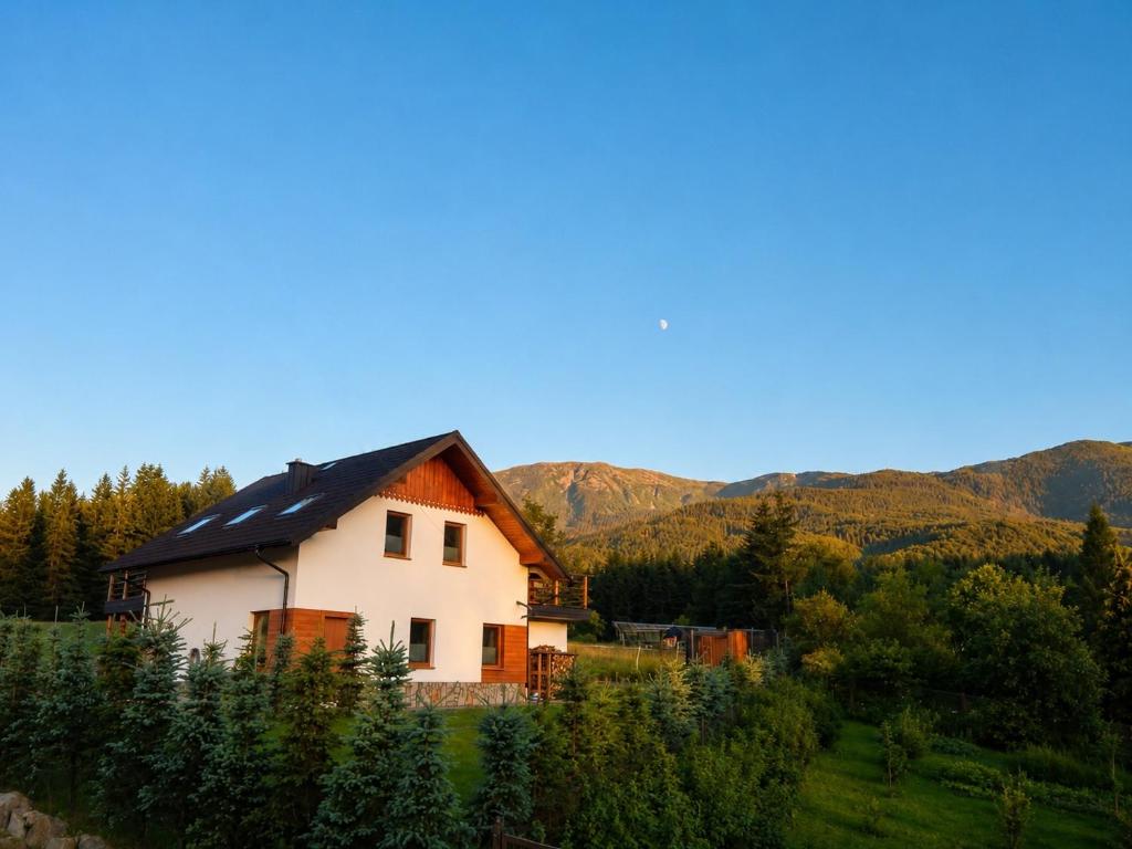 a house in a field with mountains in the background at Domek SAMI SWOI in Zawoja