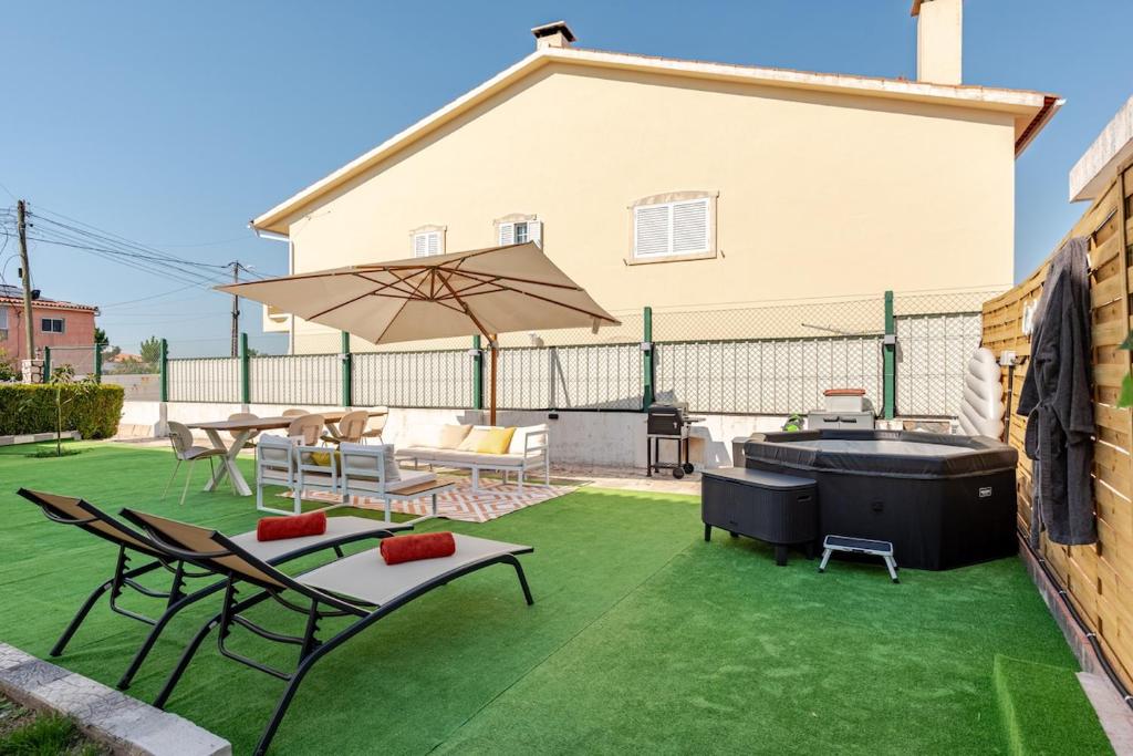 a patio with a hot tub and chairs and an umbrella at The Quinta & Studios in Quinta do Conde