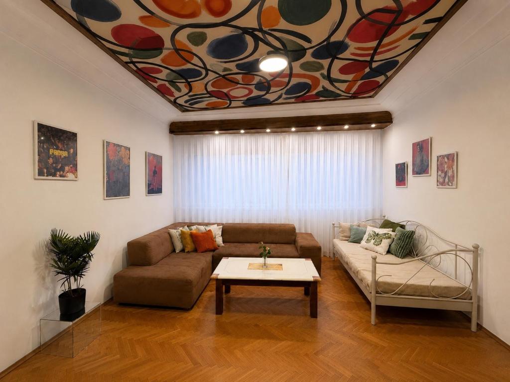 a living room with a couch and a table at The Art Ceiling Loft at Main Square in Prishtinë