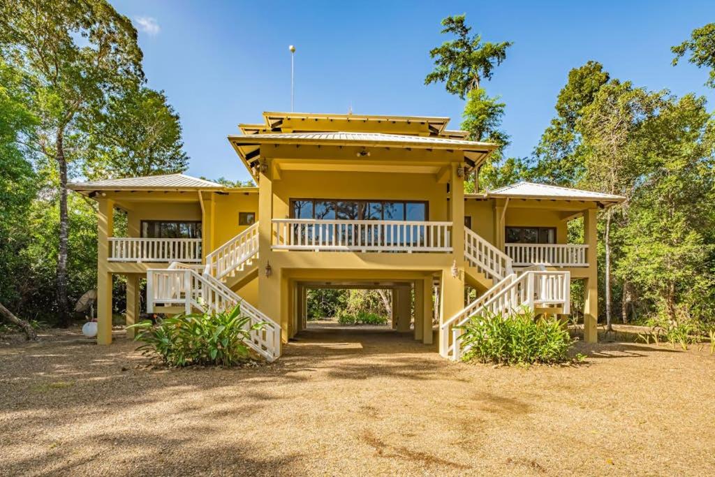 a yellow house with a large front porch and decks at The Reserve in Dangriga