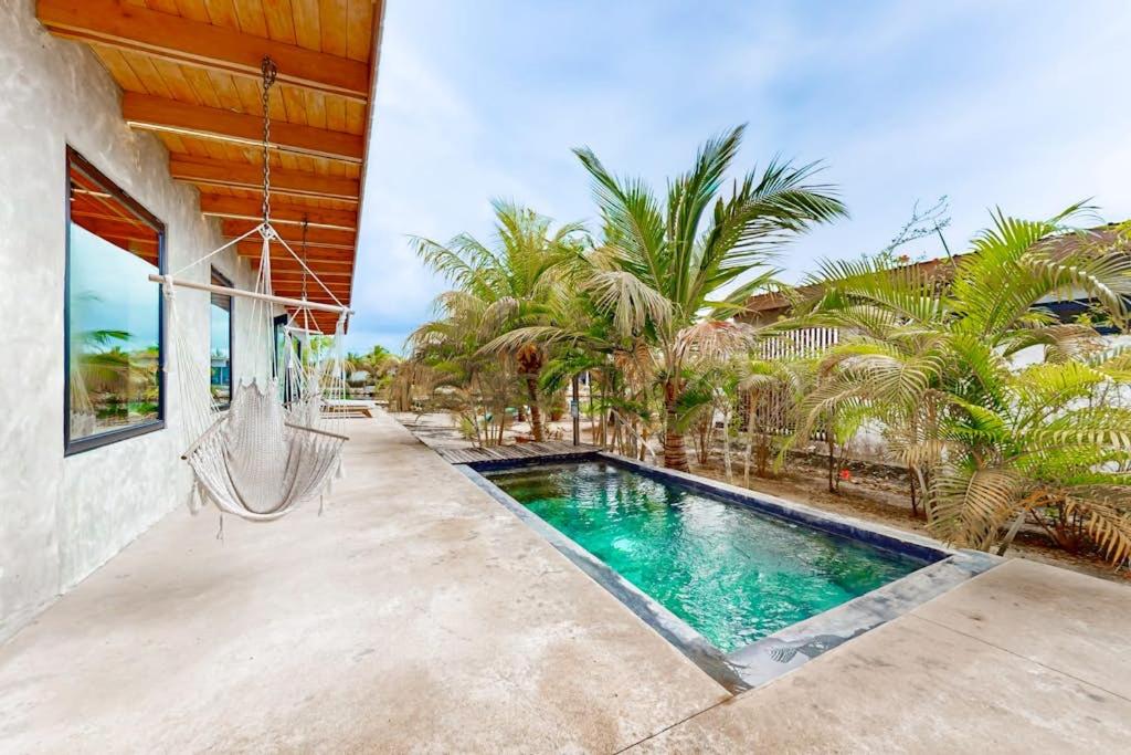 a swimming pool with a hammock on a patio at Seabird - Villa 6 in Placencia