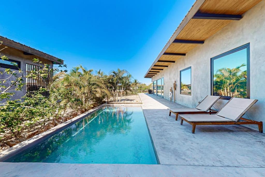 a swimming pool with lounge chairs next to a house at Seabird - Villa 26 in Placencia