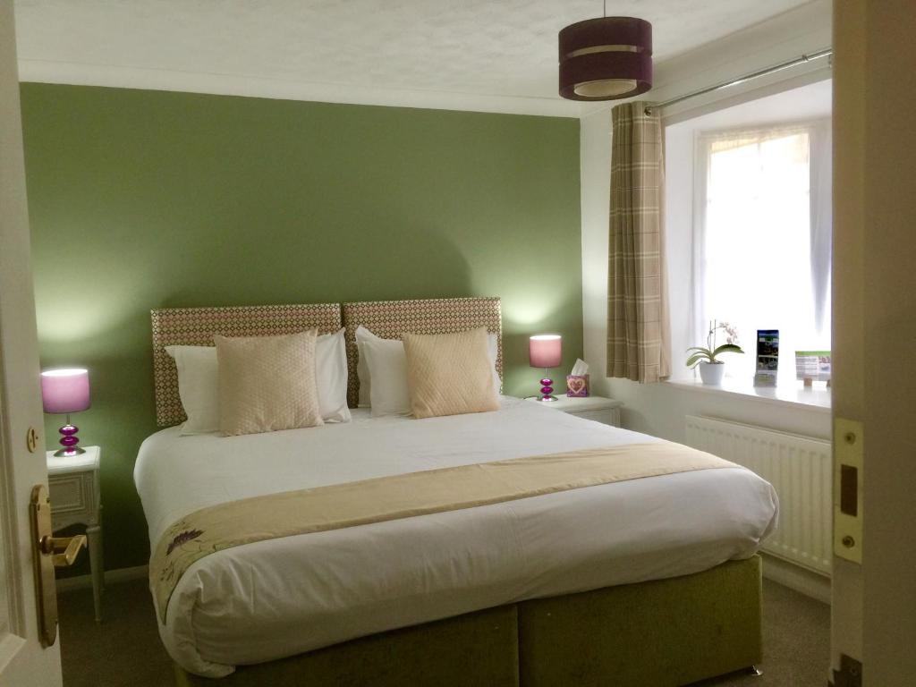 a bedroom with a large bed with a green wall at Stepping Stones B&B in Lymington