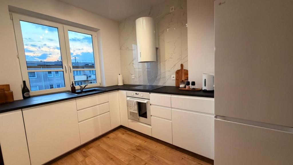 a kitchen with white cabinets and a large window at Targówek Home in Warsaw