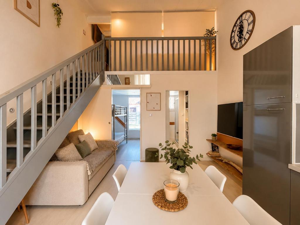 a living room with a white table and a staircase at Maison village accès mer et commerces à pieds in Le Barcarès