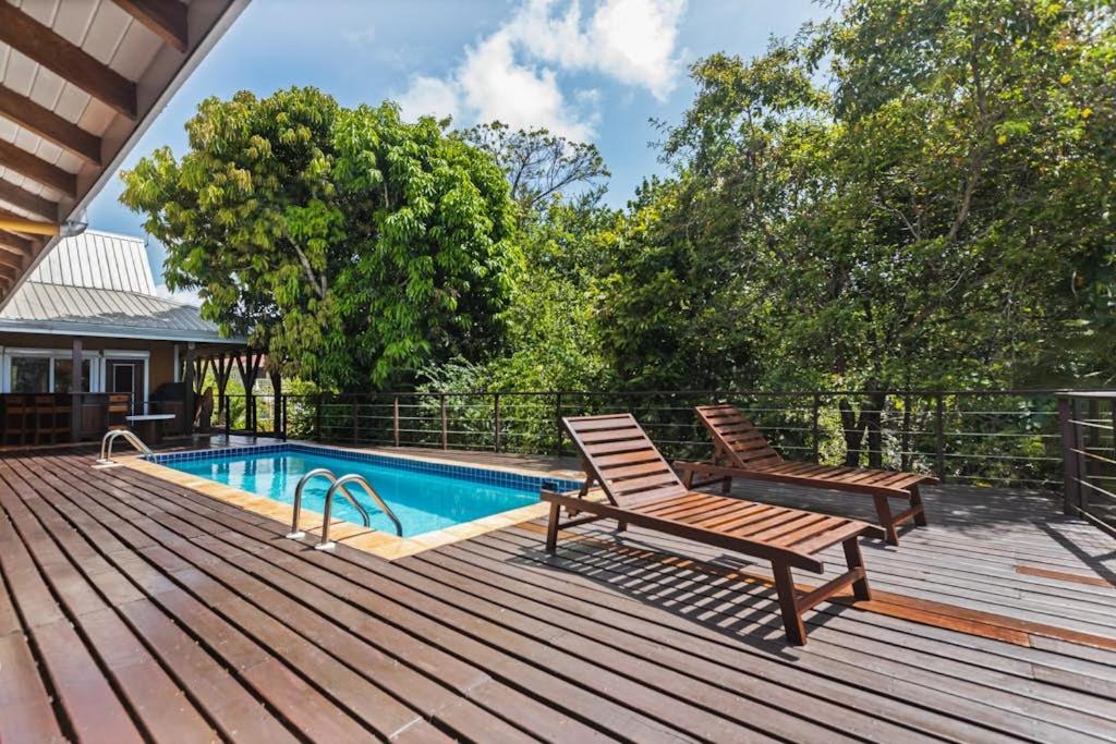 a deck with two chairs next to a swimming pool at Bougainvilla in Placencia