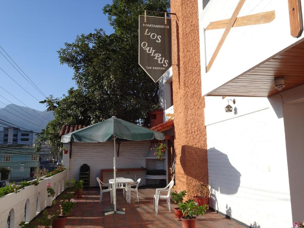 un patio con mesa y sombrilla en Apartamentos Los Quipus, en Quito