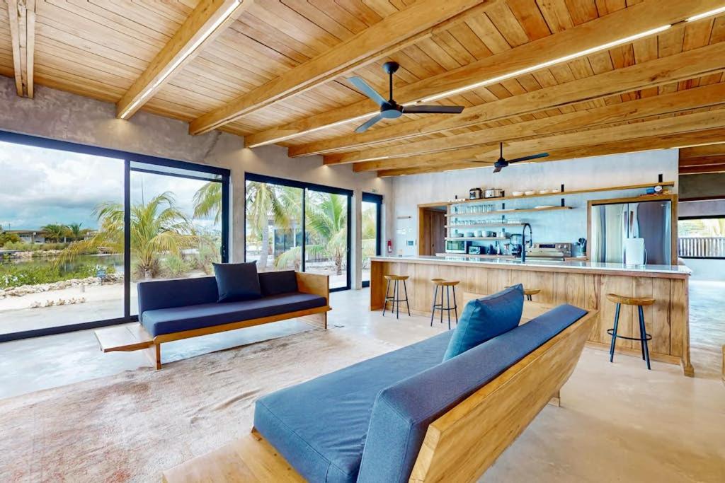 a living room with a blue couch and a kitchen at Seabird - Villa 1 in Placencia